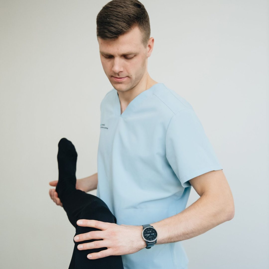 A physiotherapist helping a patient with leg exercises indoors.