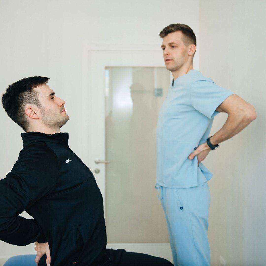 A physiotherapist instructs a patient on back exercises in a clinic setting.