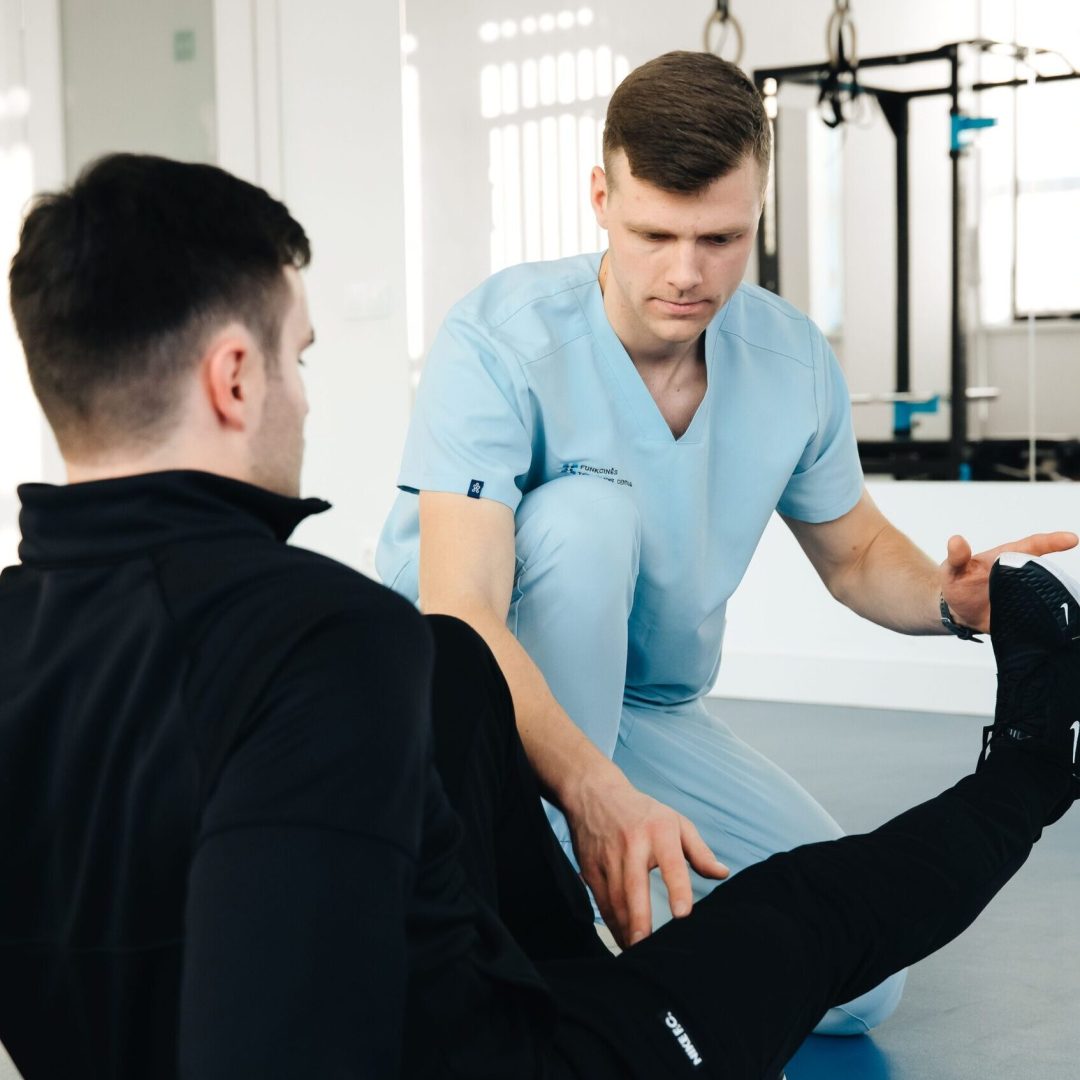 A physiotherapist assisting a patient in leg exercises during a rehabilitation session in a clinic setting.
